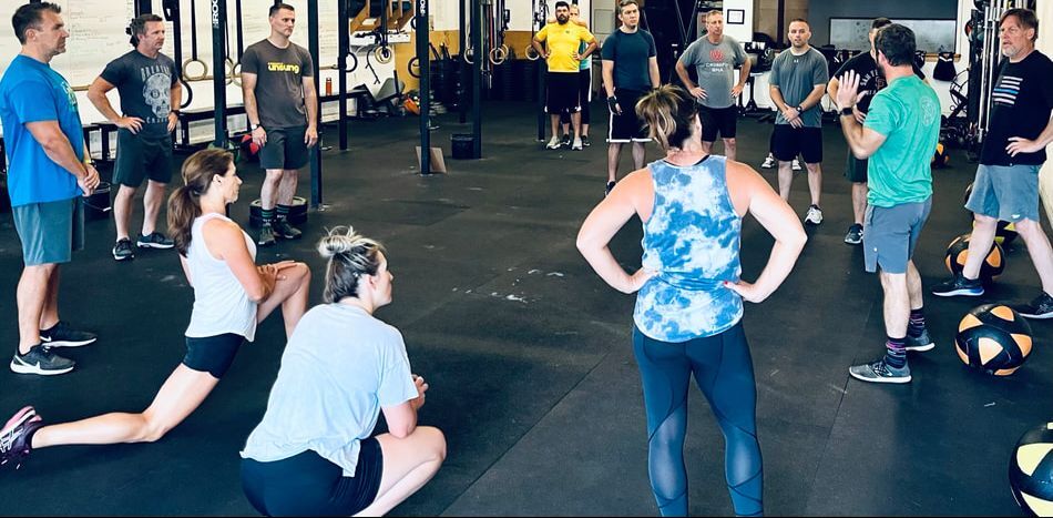 Coach briefing a CrossFit Unsung class gathered on the gym floor